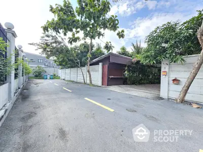 Spacious residential driveway with lush greenery and secure gate access