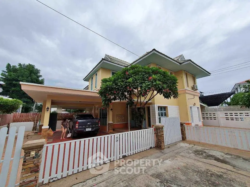Charming two-story house with carport and lush greenery in a serene neighborhood.