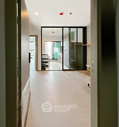 Modern apartment entrance with open layout and glass partition, leading to a bright living area.