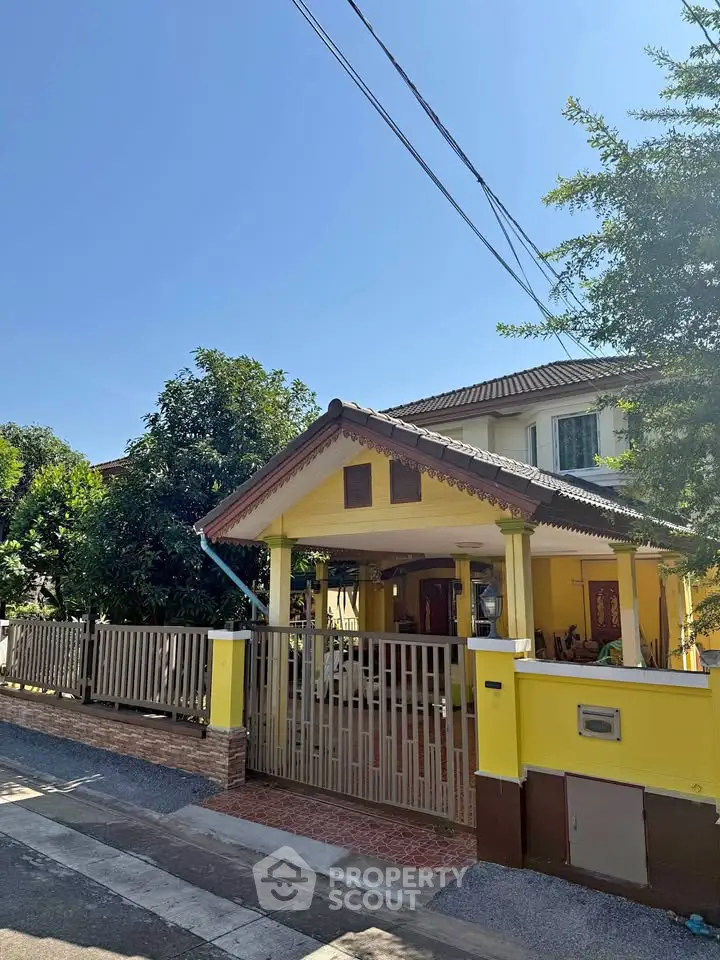 Charming yellow house with spacious front yard and gated entrance in sunny neighborhood.