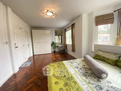 Spacious bedroom with elegant parquet flooring and large windows for natural light.