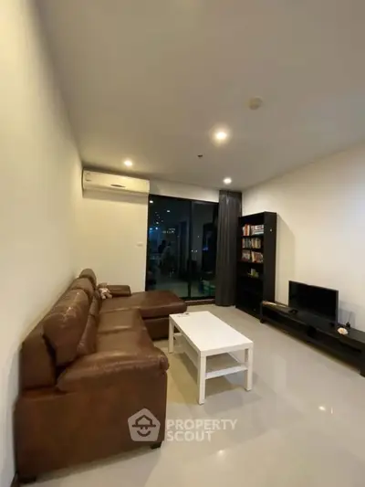 Modern living room with leather sofa, sleek TV stand, and large window for natural light.