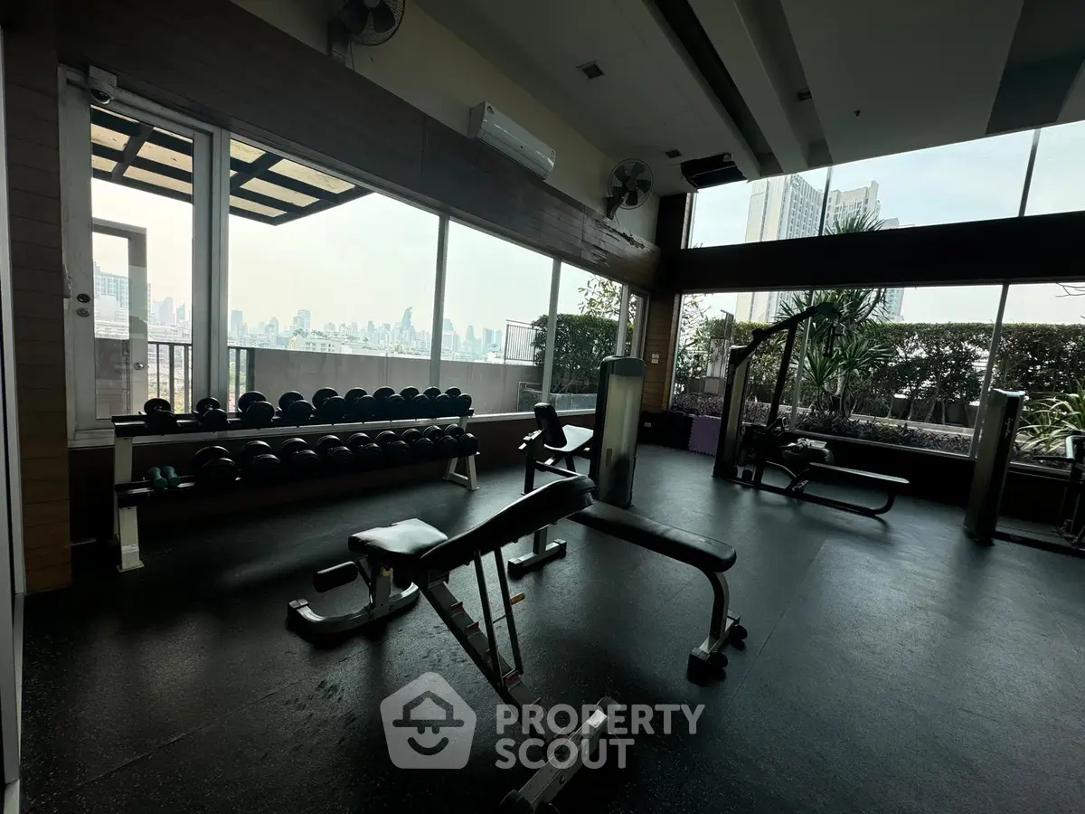 Spacious gym with city view and modern equipment in luxury apartment building.