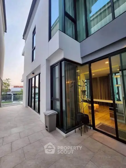 Modern exterior view of a stylish two-story home with large windows and a spacious patio area.