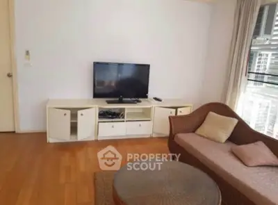 Cozy living room with modern TV setup and stylish wicker furniture in a bright apartment.