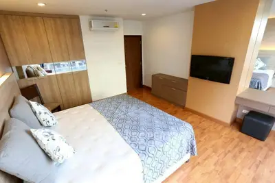 Modern bedroom with wooden flooring and wall-mounted TV in stylish apartment.
