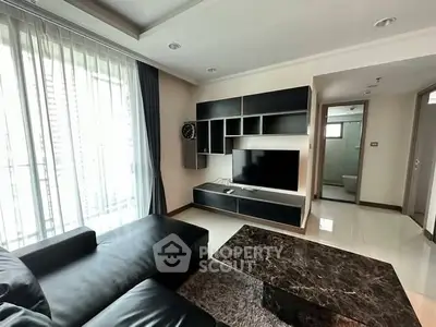 Modern living room with sleek black furniture and marble coffee table, featuring a wall-mounted TV and large windows.