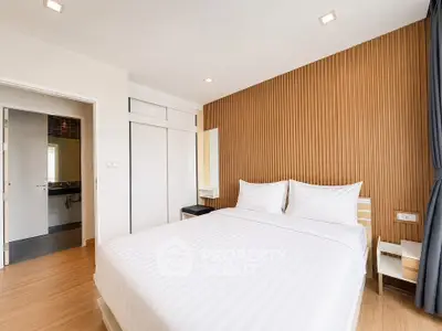 Modern bedroom with wooden accent wall and cozy white bedding