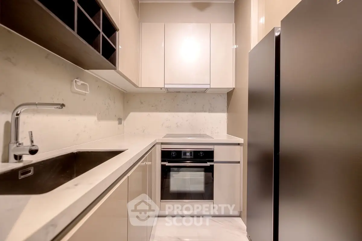 Modern kitchen with sleek cabinetry and built-in oven in a compact layout.