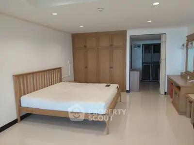 Spacious bedroom with wooden furniture and ample storage in modern apartment.