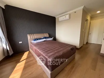 Spacious bedroom with modern decor and natural light, featuring a comfortable bed and wooden flooring.