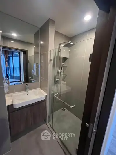 Modern bathroom with glass shower and sleek vanity in contemporary apartment.