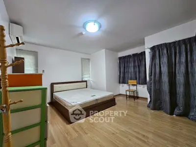 Spacious bedroom with wooden flooring and modern furnishings