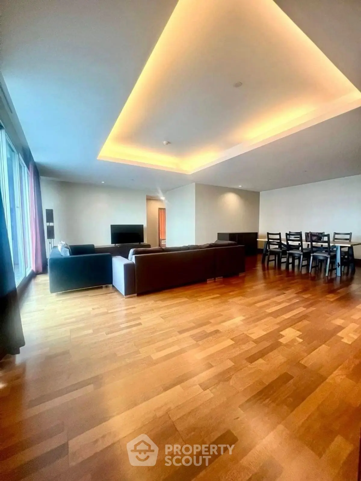 Spacious modern living room with elegant dining area and wooden flooring.