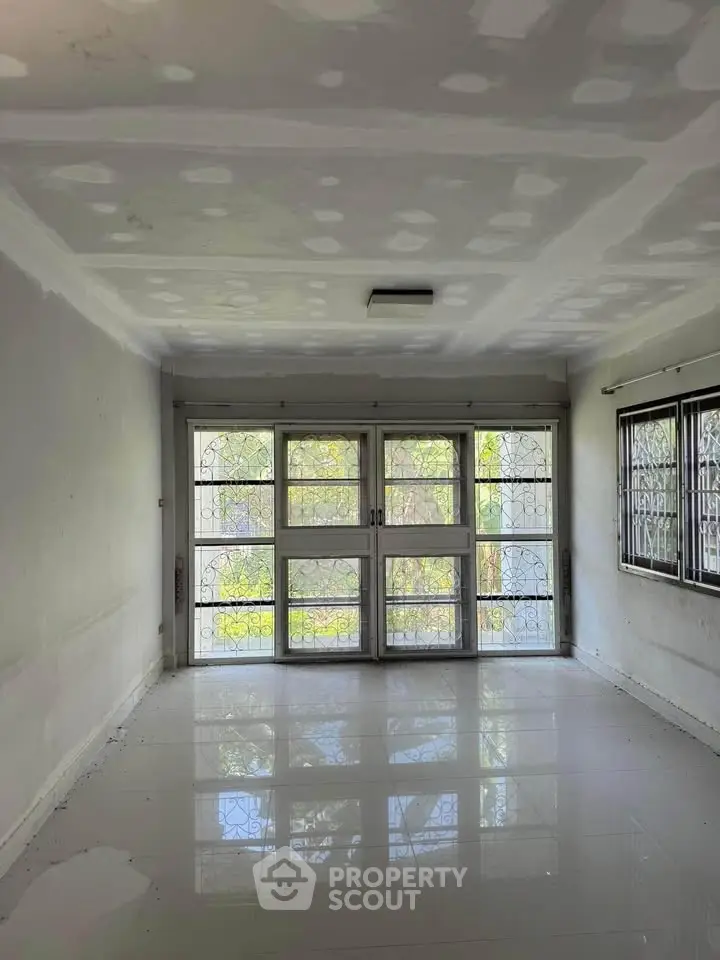 Spacious empty room with large windows and tiled floor, perfect for customization.