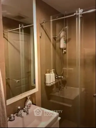 Compact bathroom with glass shower enclosure and modern fixtures.