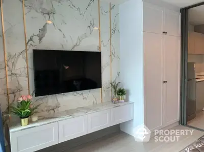 Elegant living room with marble wall accent featuring a mounted flat-screen TV and chic floating cabinet, complemented by subtle decorative plants.