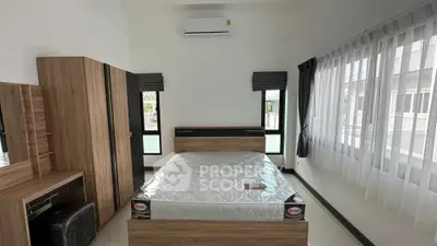 Spacious bedroom with modern furniture and large windows for natural light.