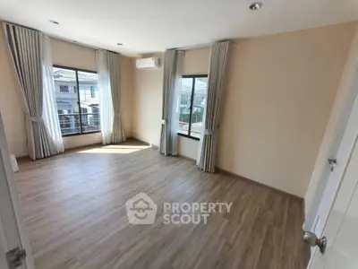 Spacious empty room with wooden flooring and large windows in modern home