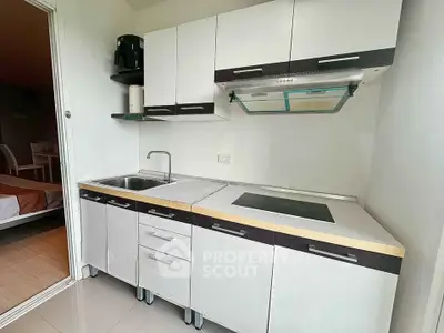 Modern compact kitchen with sleek cabinetry and induction cooktop in a cozy apartment setting.