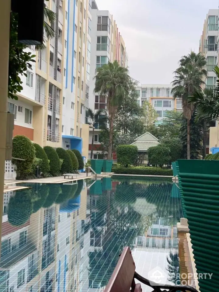 Stunning poolside view in modern residential complex with lush greenery and tall buildings.