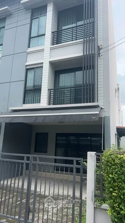Modern three-story townhouse with sleek design and gated entrance, perfect for urban living.