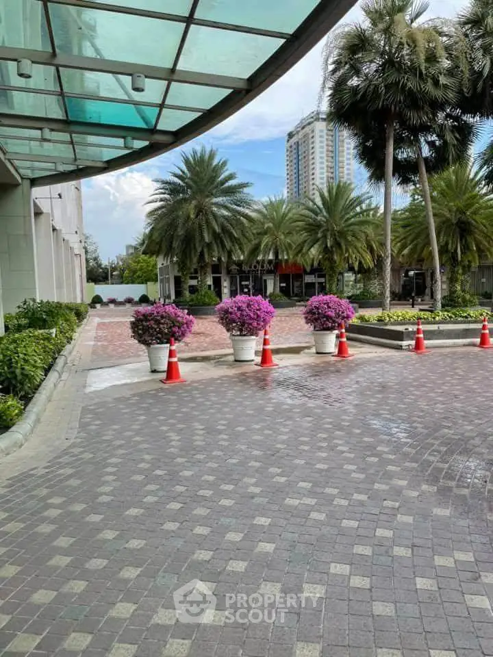 Elegant building entrance with lush landscaping and palm trees, perfect for luxury living.