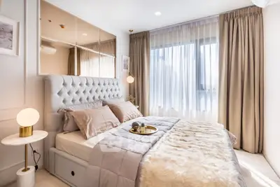 Luxurious bedroom with plush bedding and elegant decor, featuring large windows and soft lighting.