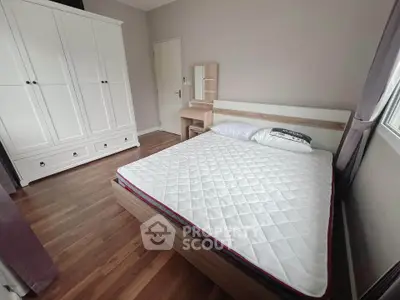 Spacious bedroom with modern furniture and natural light, featuring a large wardrobe and wooden flooring.