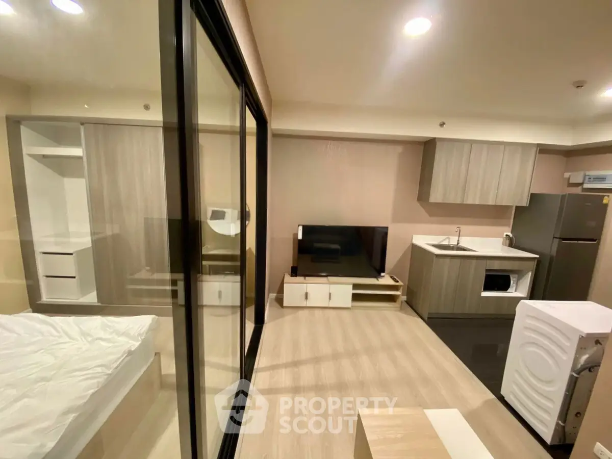 Modern studio apartment with open layout, featuring sleek kitchen and cozy living area.