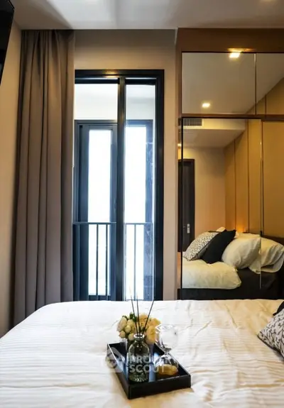 Modern bedroom with mirrored closet and balcony access, featuring elegant decor and cozy ambiance.