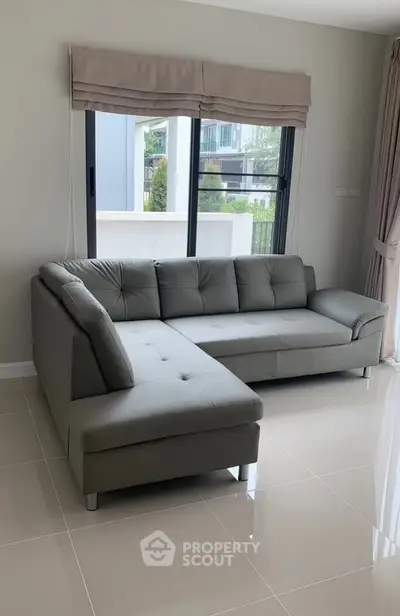 Modern living room with sleek gray sectional sofa and large window view.