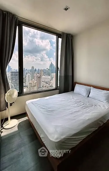 Modern bedroom with large window offering stunning city view in high-rise apartment.