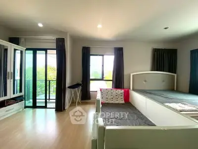 Spacious bedroom with large windows and balcony access, featuring modern furnishings and natural light.