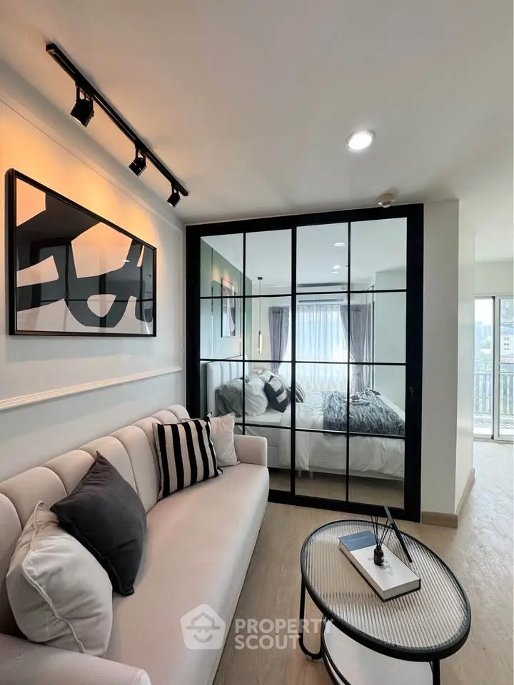 Modern living room with stylish decor and large mirrored wall reflecting natural light.