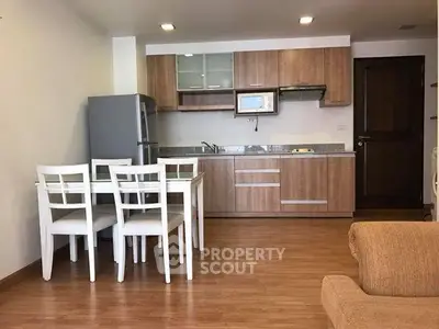 Modern kitchen with wooden cabinets and dining area in open layout apartment.