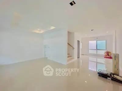 Spacious modern living room with glossy tile flooring and staircase in a bright open layout.