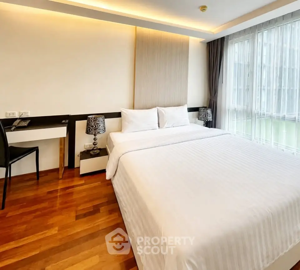 Spacious bedroom with modern decor and large windows for natural light.