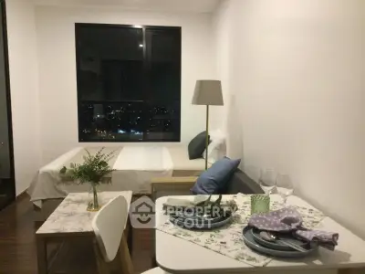 Cozy studio apartment with night city view, featuring a stylish dining area and comfortable bed.