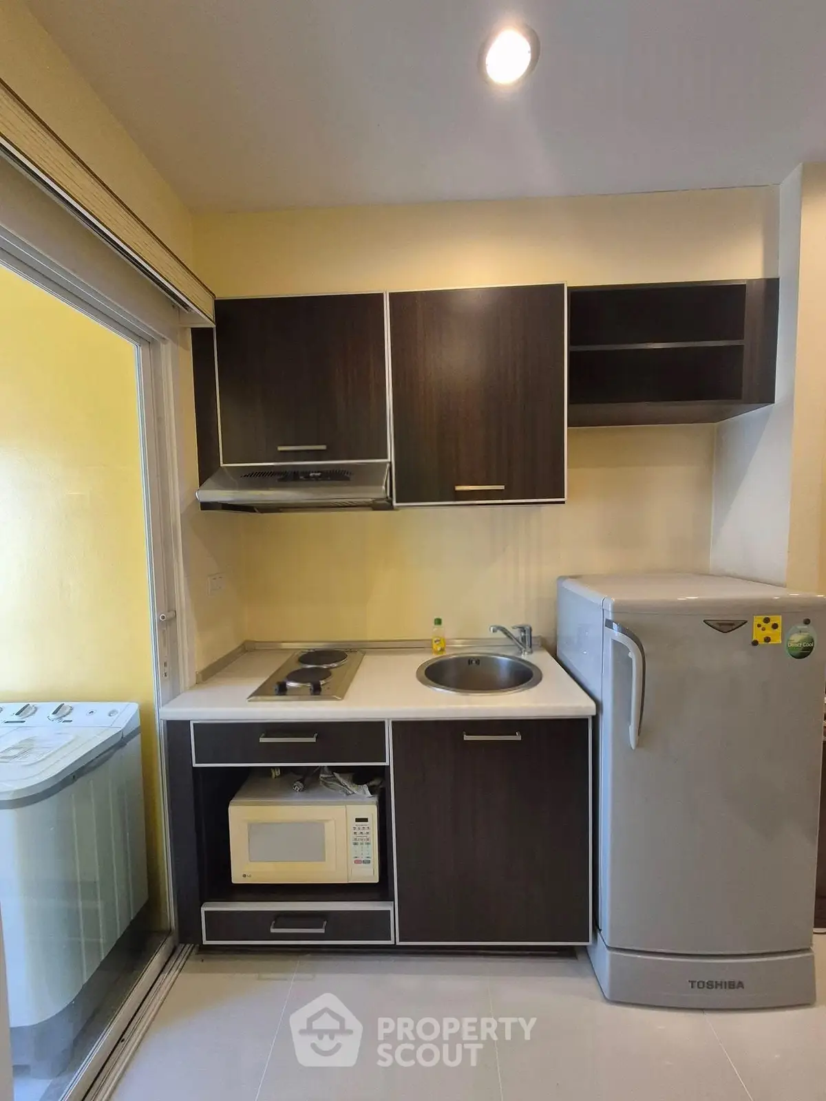 Modern compact kitchen with sleek cabinets and appliances, featuring a microwave and fridge, ideal for urban living.