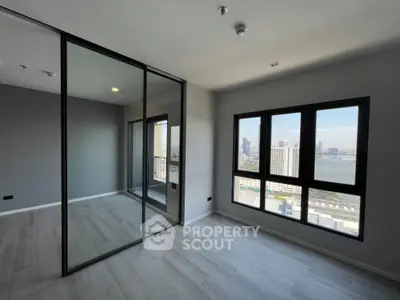 Spacious modern bedroom with large windows offering stunning city and river views.