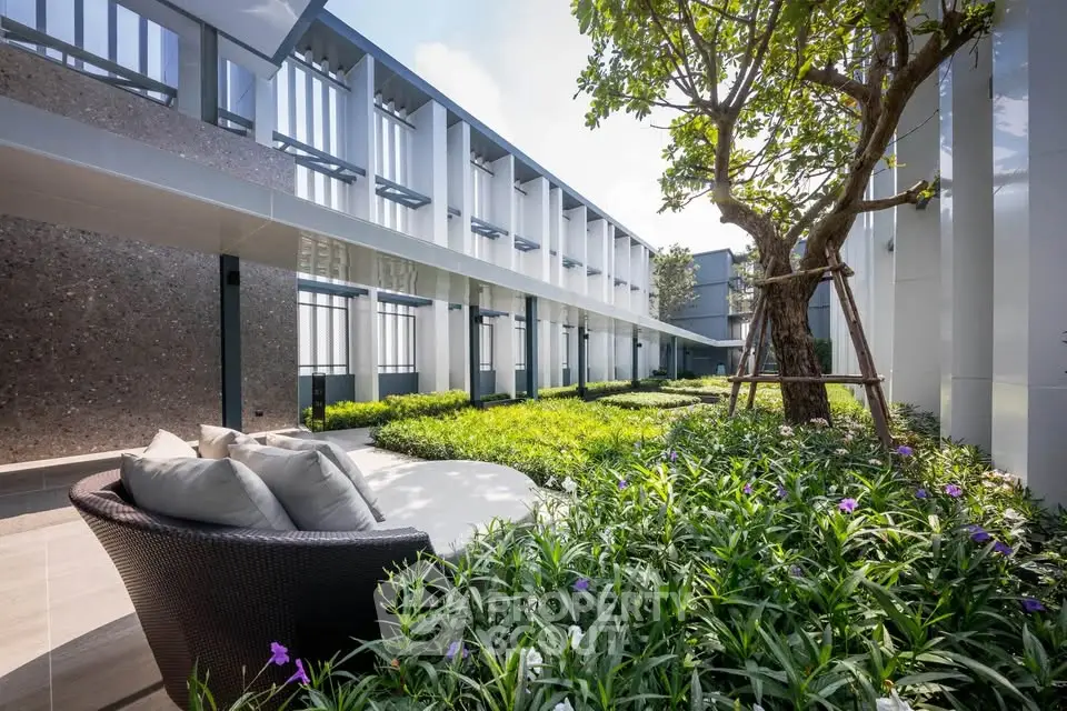 Modern building exterior with lush garden and seating area, perfect for relaxation and outdoor enjoyment.