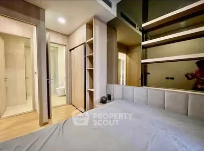 Modern bedroom with sleek design and built-in storage, featuring a view into an ensuite bathroom.