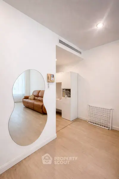 Modern living room with unique mirror and leather sofa, showcasing minimalist design.