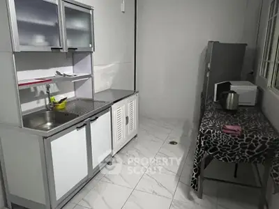 Compact kitchen with modern cabinets and appliances, featuring a sleek countertop and tiled flooring.