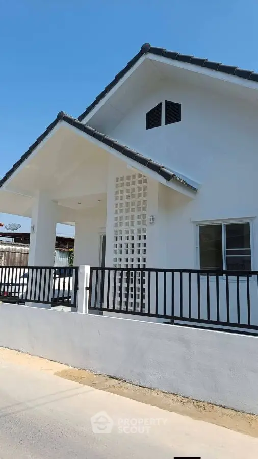 Charming modern house exterior with sleek design and spacious porch under clear blue sky.