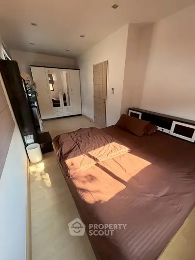 Cozy bedroom with brown bedding and mirrored wardrobe, perfect for relaxation.
