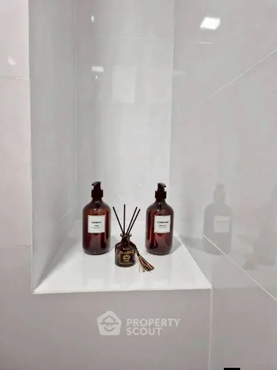 Elegant bathroom corner with stylish toiletries and diffuser on a sleek white shelf.