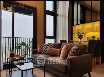 Modern living room with large windows and balcony offering stunning city views, featuring stylish decor and open layout.