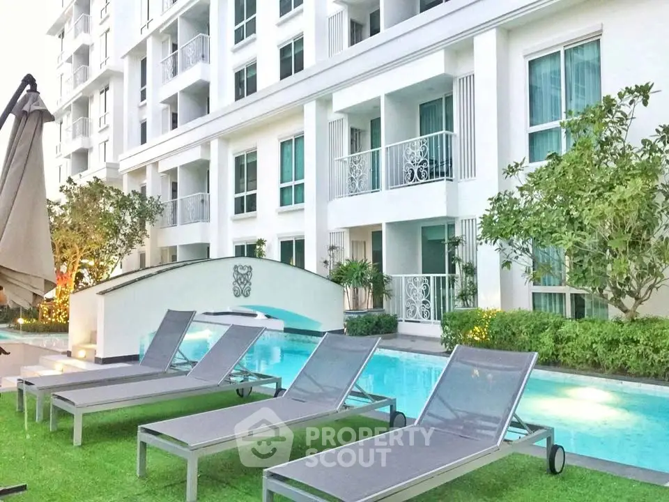 Luxurious apartment complex with poolside lounge chairs and lush greenery